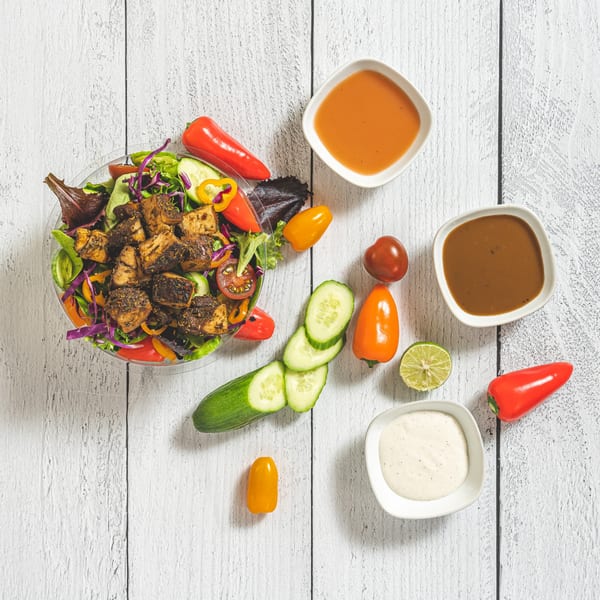 Suzie's Fusion Cuisine Caribbean jerk chicken salad with fresh vegetables and three sauces.