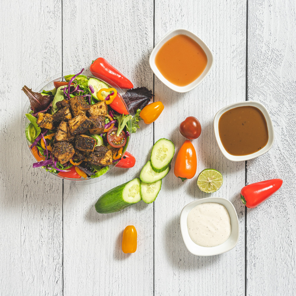 Suzie's Fusion Cuisine Caribbean jerk chicken salad with fresh vegetables and three sauces.