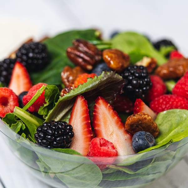 Close-up of a vibrant Suzie's Fusion Cuisine salad with mixed greens, berries, and pecans.